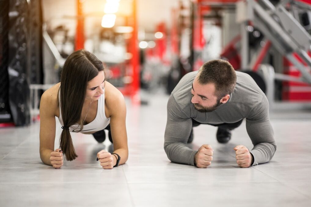 Un hombre y una mujer realizan el ejercicio Plank, diseñado para todos los grupos musculares